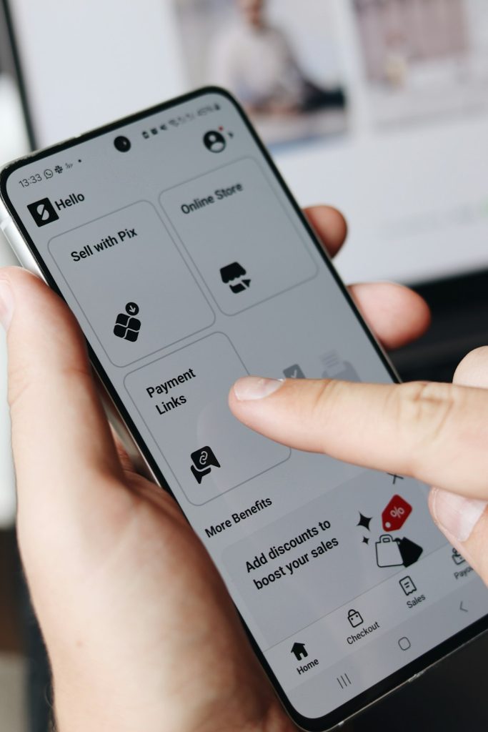 A close-up shot of a person using a smartphone displaying the SumUp app interface. The user is navigating through options such as Sell with Pix, Online Store, and Payment Links. The clean design and user-friendly layout of the app make it ideal for small business owners to manage their sales and transactions effortlessly.