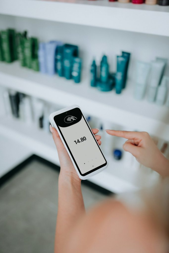 Contactless card payment being processed using a SumUp Terminal card reader in a clean, product-filled salon.