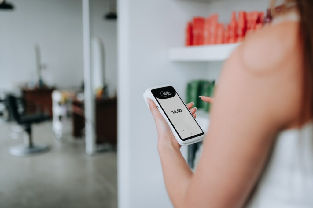 Minimalist shot of a client using a SumUp card reader surrounded by beauty products.